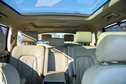 Seven-seater new car interior. Seven white back seats. New car inside. Car cleaning theme. Luxury car rear leather seats row. Interior of modern, clean expensive car. Passenger seats with leather.