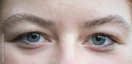 Close-up of a human eye with vibrant blue iris and detailed patterns, reflecting colors and shapes from the surrounding environment