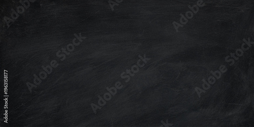 A dark grunge blackboard background with a rough vintage chalk texture on a black chalkboard surface creates a blank old paper backdrop for a dirty gray canvas design