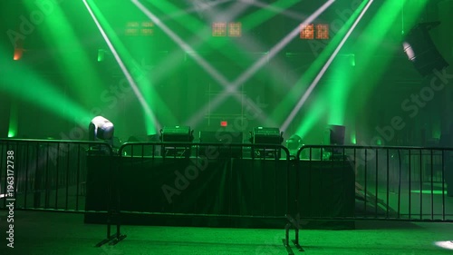 Bright green spotlights cut through the dark atmosphere of an empty stage or venue. The dynamic beams create circular patterns on the floor, evoking an energetic mood for a concert or live event.
