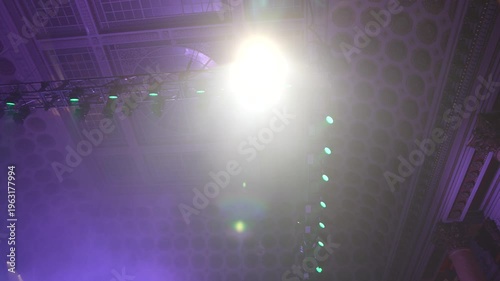Bright green spotlights cut through the dark atmosphere of an empty stage or venue. The dynamic beams create circular patterns on the floor, evoking an energetic mood for a concert or live event.
