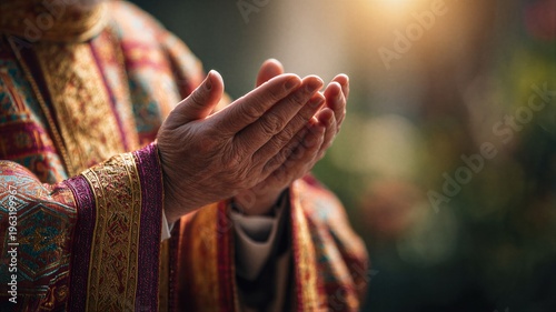 Priest in ornate liturgy vestment with hands held in prayer. Christian clergyman performing religious rite. Devotion to Easter faith and spiritual meditation in church interior setting.
