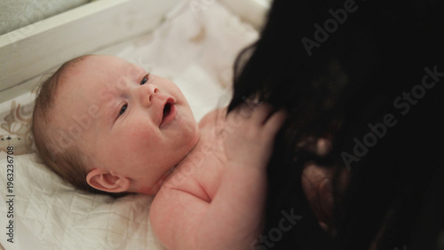 Fotografia Joyful baby giggling while being tickled by a parent's dark hair