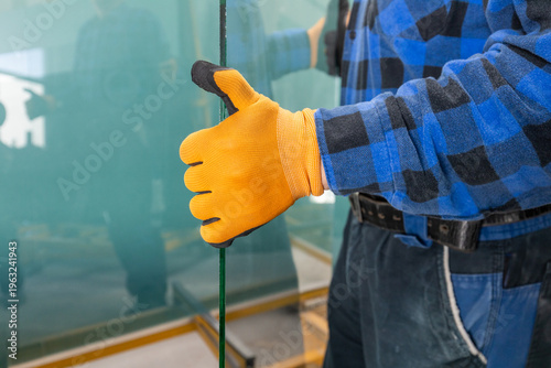 Canvas Print The glassmaker in the workshop holds a large piece of glass in his hands