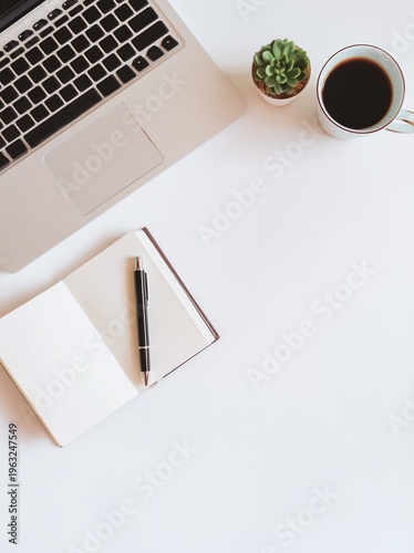 Minimal home office desk flat lay featuring a laptop, open notebook, pen, small succulent plant, and a cup of coffee on a clean white surface