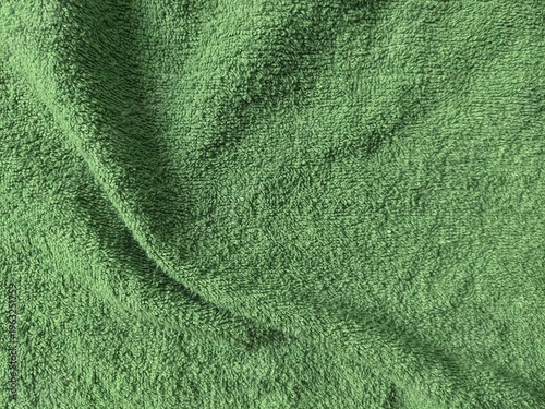 Natural green cotton towel background texture. Soft fluffy fabric surface with gentle textile detail.