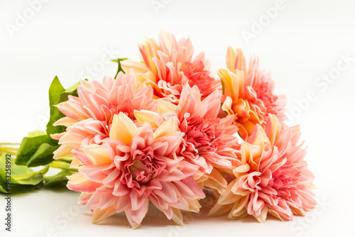 Tableau sur toile A high-quality studio shot of a vibrant artificial peach dahlia bouquet featuring multiple blooming flower heads and green leaves