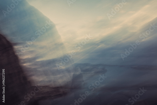 Foto Dreamlike motion blurred coastal scene with soft pastel light, water, rocks and a ghosted human figure