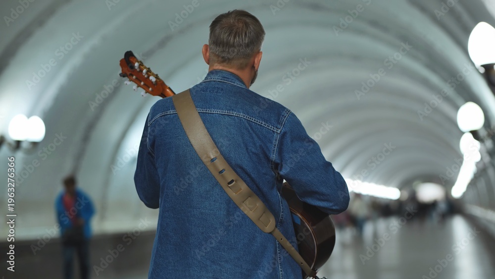 Αυτοκόλλητο Man walking in subway passage with guitar, urban musician life and music perform