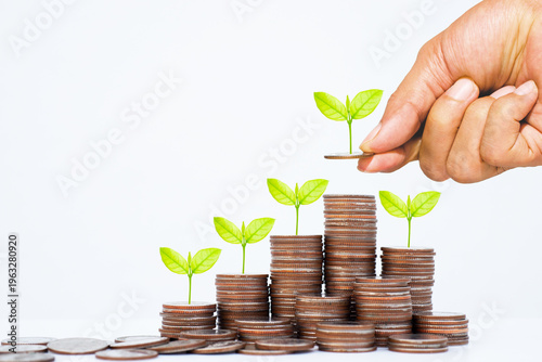 Close-up of a hand placing coins on a growing stack with green plants, representing financial growth, savings, and investment strategy. Concept wealth management, passive income, ESG business success.