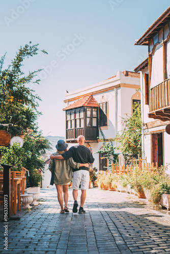 Middle aged couple walking hand in hand along narrow street in Kas town historical center. Romantic travel, love relationship, honeymoon vacation and happy retirement lifestyle concept.