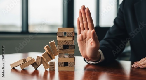 A person prevents a wooden tower from collapsing with outstretched hand