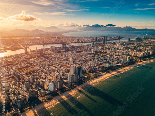 sunny sunset in Vietnamese coastal Da Nang city, My Khe sand beach and touristic My An and Son Tra district with modern skyscraper hotels and resorts, blue sea of Danang, Vietnam, aerial drone view 4k
