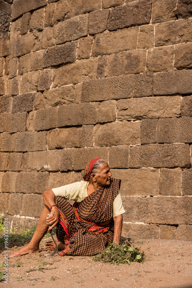 Fototapeta premium Senior woman working in front stone wall