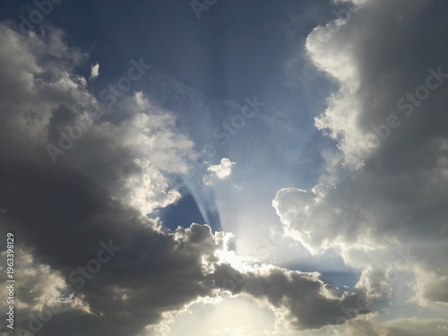 Sunbeams breaking through dramatic dark clouds in a deep blue sky, divine light effect, nature background