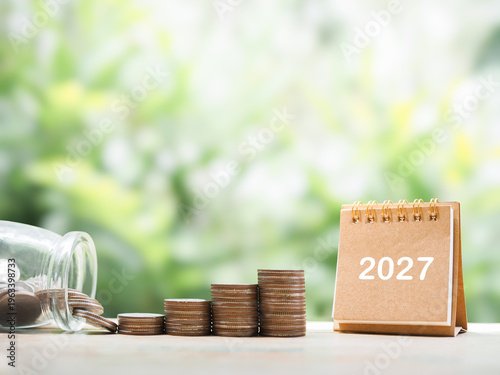 2027 desk calendar and stack of coins. The concept of saving money, Financial, Investment and Business growing in new year 2026