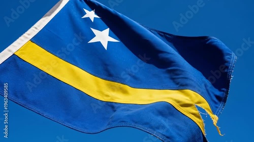 Blue flag with yellow stripe and stars waving in clear blue sky