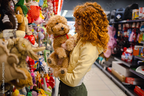 Photos Young woman with poodle in pet shop