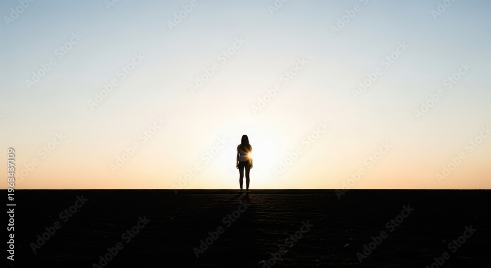 Fototapeta premium Lone figure silhouetted against a vibrant sunset, standing on a dark horizon.