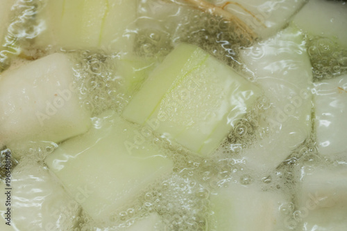 Winter melon boiling in a pot of hot water, bubbling vigorously with steam, showing cooking process