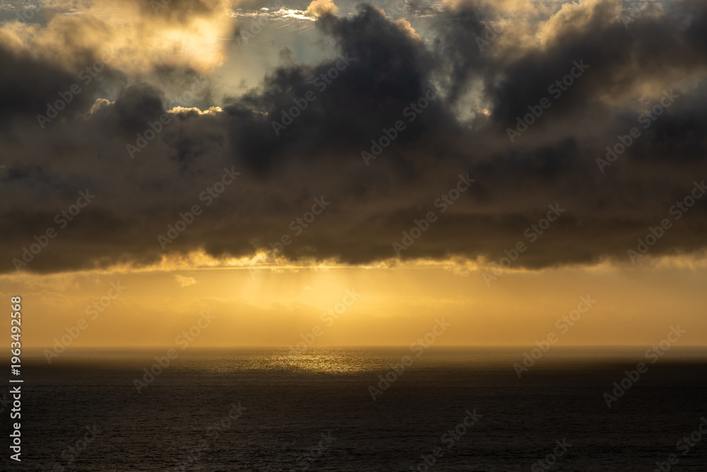 Fototapeta premium A view out over the ocean at sunset, with storm clouds overhead