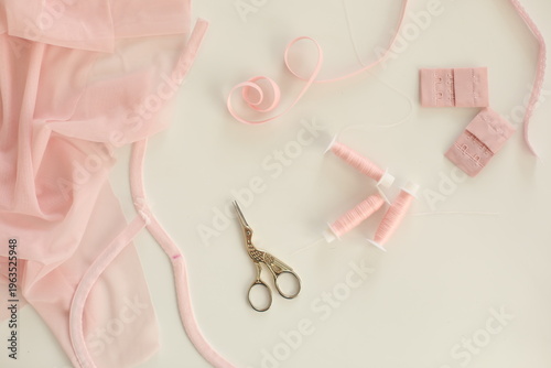 Flat lay composition with scissors and sewing supplies on the table. Crafting essentials for sewing projects with fabric, threads, and tools, ribbon tapes on white background.