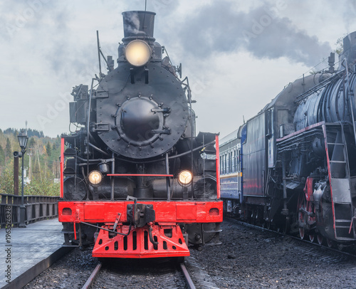 Old steam train stands by the platform.
