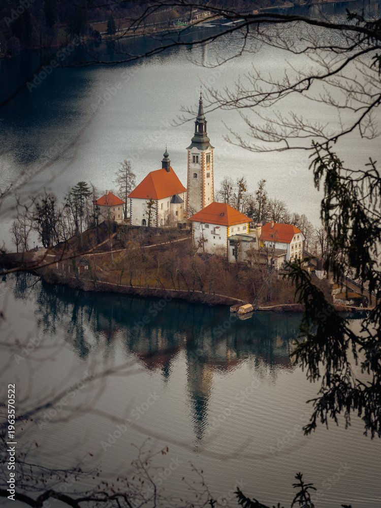 Fototapeta premium Lake Bled Island Through Branches, Slovenia, Winter Scene with Natural Framing