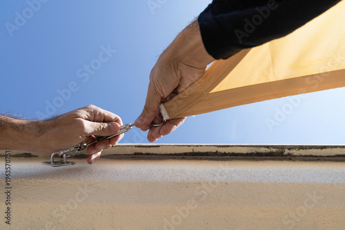 Middle-aged man installing a sail shade on a building's terrace.
DIY, lifestyle, people, home life