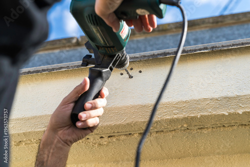 An unrecognizable person installing a support bracket for an outdoor awning on their penthouse terrace.
People, lifestyles, DIY projects