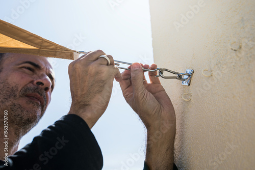 Middle-aged man installing a sail shade on a building's terrace.
DIY, lifestyle, people, home life