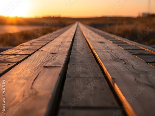 A serene wooden boardwalk stretches into the distance at sunset