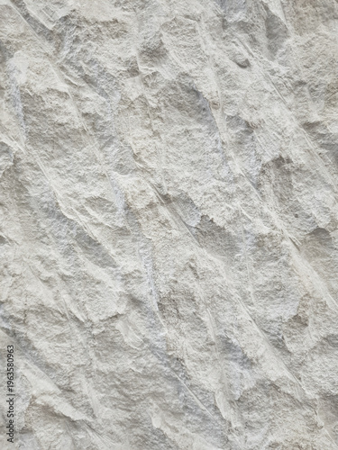 Fotografie Background of rough ivory white limestone wall texture with diagonal carved lines, up close