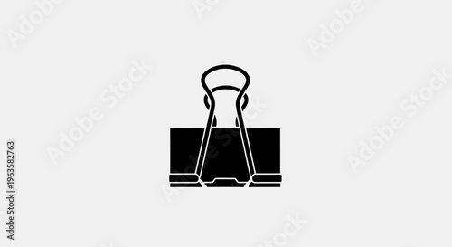 Black binder clip on a gray background, isolated object, office supplies