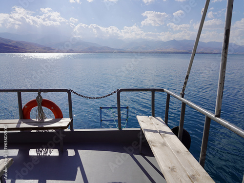 The deck of a ferry offers a scenic view of the bright blue waters of Lake Van and the distant, hazy mountains surrounding Akdamar Island in eastern Turkey