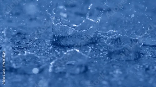 Close-up rain, raindrops falling in a large puddle. rain season, slow motion heavy rain splashing on deep blue water surface, heavy rain on water.