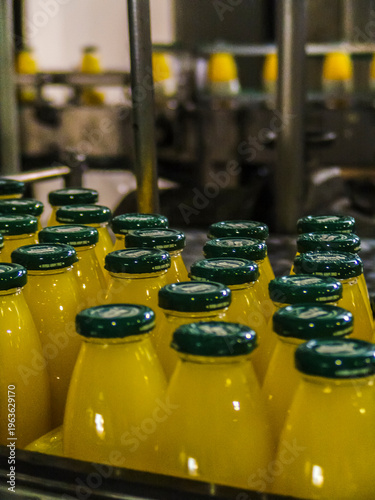 Canvastavla Industrial beverage production line in a factory, showing plastic bottles filled with juice moving along an automated conveyor system