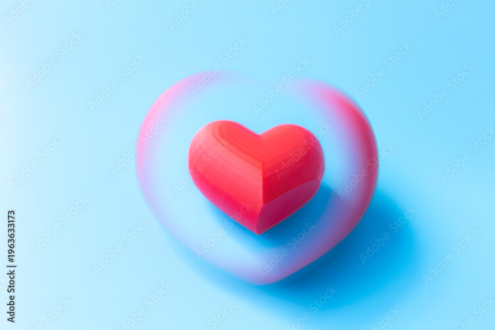 Obraz premium Red heart shape with a blurred outline on a light blue background, symbolizing love and affection in a minimalist design suitable for various themes
