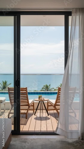 Luxury balcony with wooden chairs and infinity pool overlooking the turquoise ocean and tropical palm trees under a blue sky