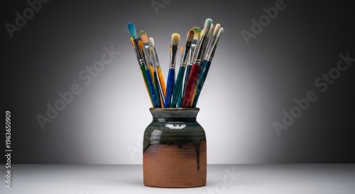 Colorful paintbrushes in ceramic pot on artist studio shelf