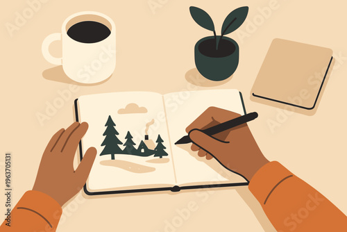 Artist sketching a cozy winter cabin scene in a notebook with coffee and plant