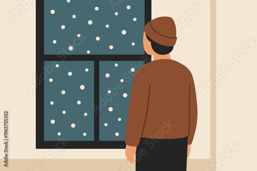 Person in beanie watches snowfall through a window on a winter evening