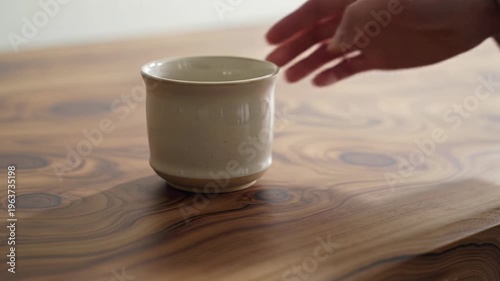 Wallpaper Mural Dark brown wood surface, natural grain, hand places an off-white ceramic mug. Diffused daylight, gentle shadows, bokeh. Rack focus video highlights natural materials and artisanal quality, concept of Torontodigital.ca