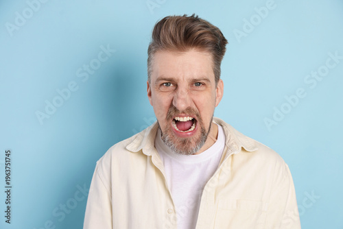 Картината върху платно Portrait of resentful man screaming on light blue background