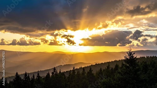 A breathtaking sunset over mountains, with dramatic clouds and silhouetted trees.