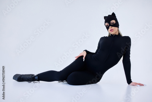 Confident woman in feline costume. Female model in black bodysuit with cat accessories. Stylish female model poses confidently in feline themed outfit with glamourous lighting