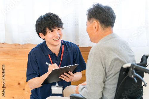 Foto A male caregiver interviews a senior man in a wheelchair.