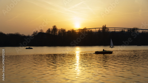Tranquil evening landscape showing boats and mirrored sunset reflection Maschsee Hanover