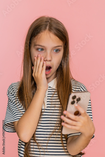 Obraz na plátně Young child girl reads a surprising message with unexpected news on smartphone, eyes wide open in astonishment clearly expressing disbelief shock, gasping with amazement