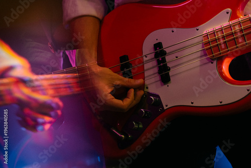 Schilderij op canvas Close-up of hands playing red electric bass guitar on stage